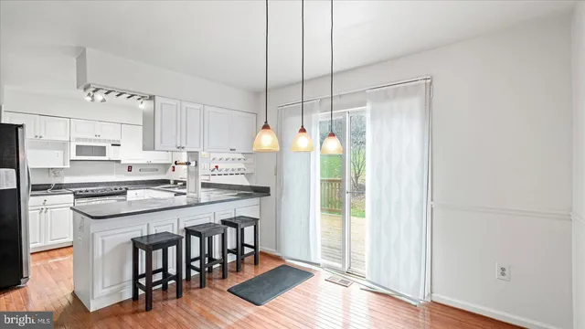 a kitchen with stainless steel appliances granite countertop a refrigerator a stove a sink dishwasher and white cabinets with wooden floor