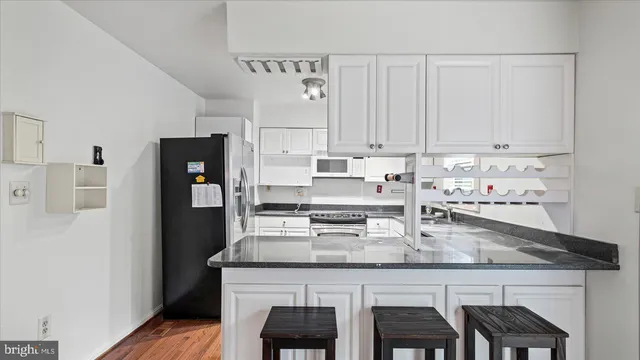 a kitchen with stainless steel appliances granite countertop a table chairs stove and refrigerator
