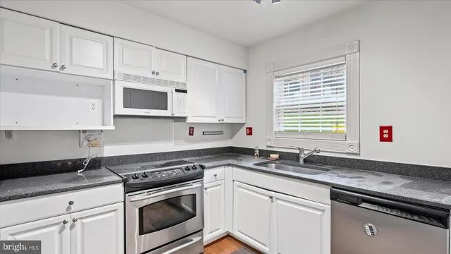 a kitchen with granite countertop white cabinets and white appliances
