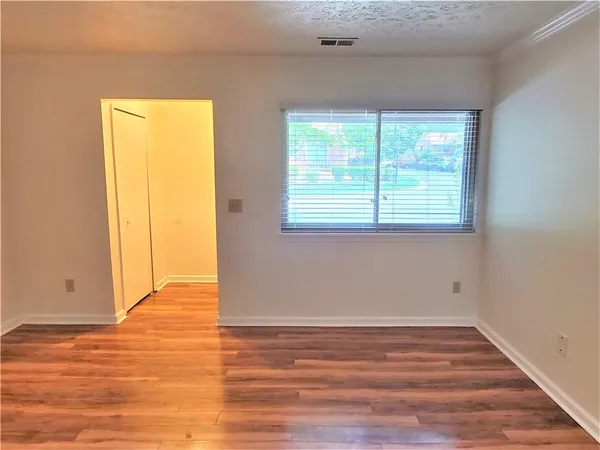 an empty room with wooden floor and windows
