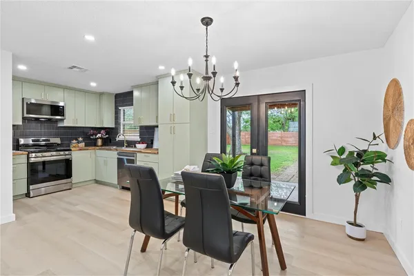 a kitchen with granite countertop stainless steel appliances dining table and a refrigerator