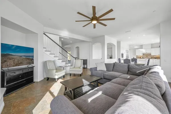 a living room with furniture and a flat screen tv with kitchen view