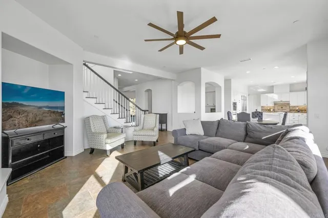a living room with furniture and a flat screen tv with kitchen view