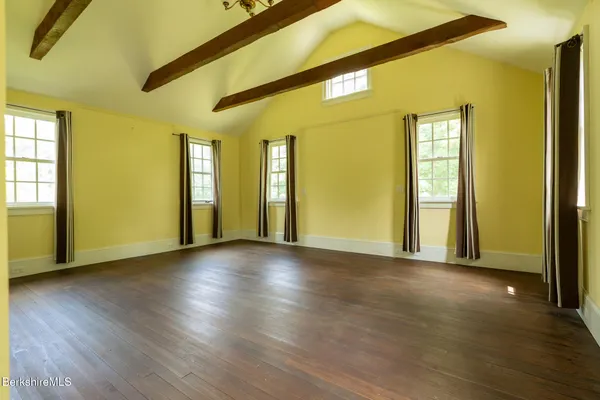 a view of an empty room with window and wooden floor