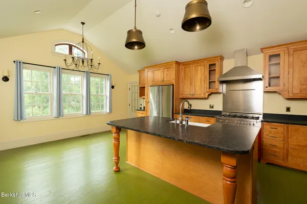 a view of a kitchen counter top space with stainless steel appliances wooden floor and windows