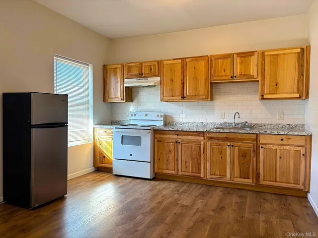 a kitchen with granite countertop a refrigerator and a stove top oven