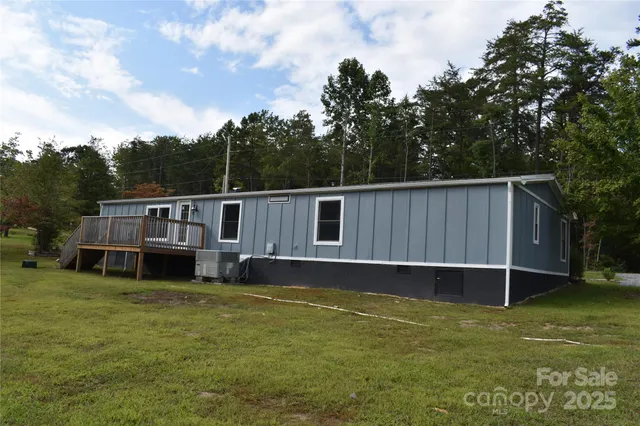 a backyard of a house with wooden fence and large trees
