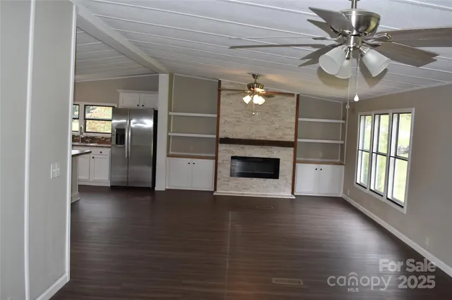 a view of a livingroom with a ceiling fan a fireplace and wooden floor