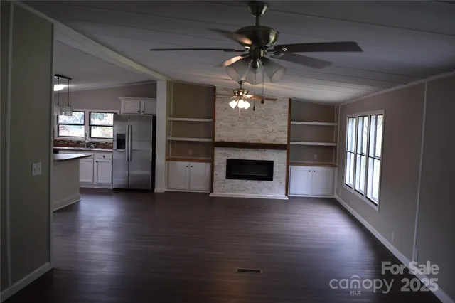 an empty room with wooden floor a ceiling fan and windows