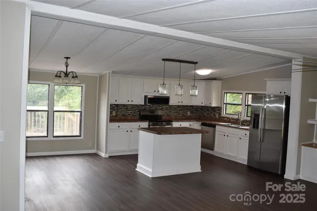 a kitchen with stainless steel appliances granite countertop a refrigerator a sink dishwasher a stove and white countertops with wooden floor