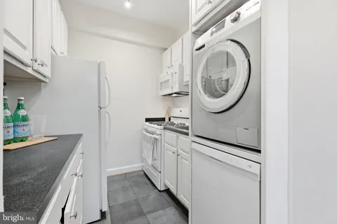 a kitchen with stainless steel appliances granite countertop a sink a washer and dryer