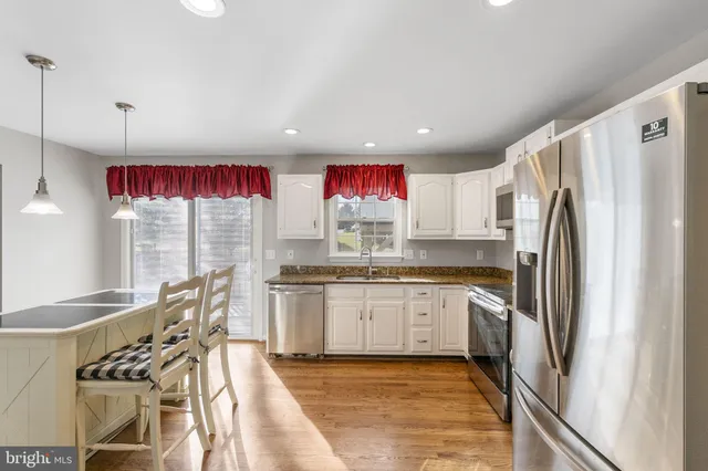 a kitchen with stainless steel appliances granite countertop a sink a stove and a refrigerator