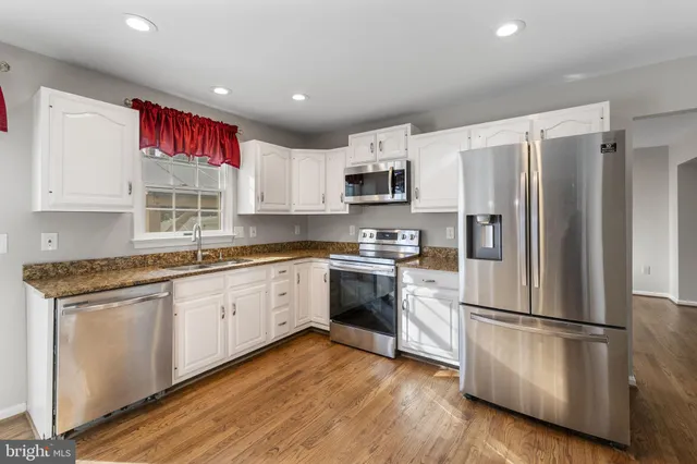 a kitchen with cabinets stainless steel appliances a sink and a window