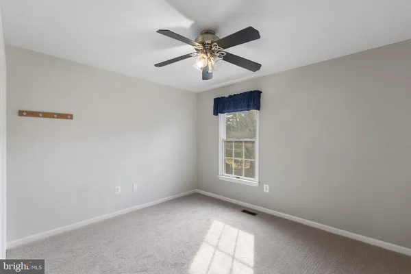 an empty room with window and ceiling fan