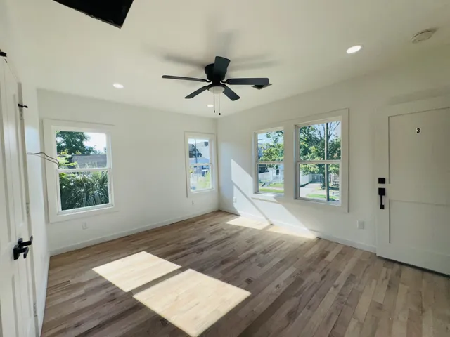 a view of empty room with wooden floor and fan