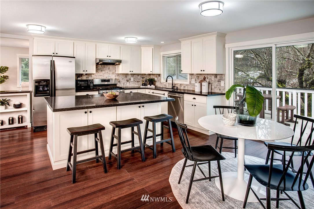 24326 Meridian Avenue South Bothell, WA 98021 - Photo 11 of 40 a kitchen with stainless steel appliances granite countertop a dining table chairs refrigerator and sink