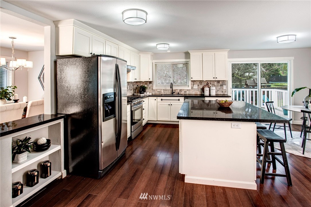 24326 Meridian Avenue South Bothell, WA 98021 - Photo 10 of 40 a kitchen with stainless steel appliances a refrigerator a stove a sink dishwasher with a dining table and wooden floor