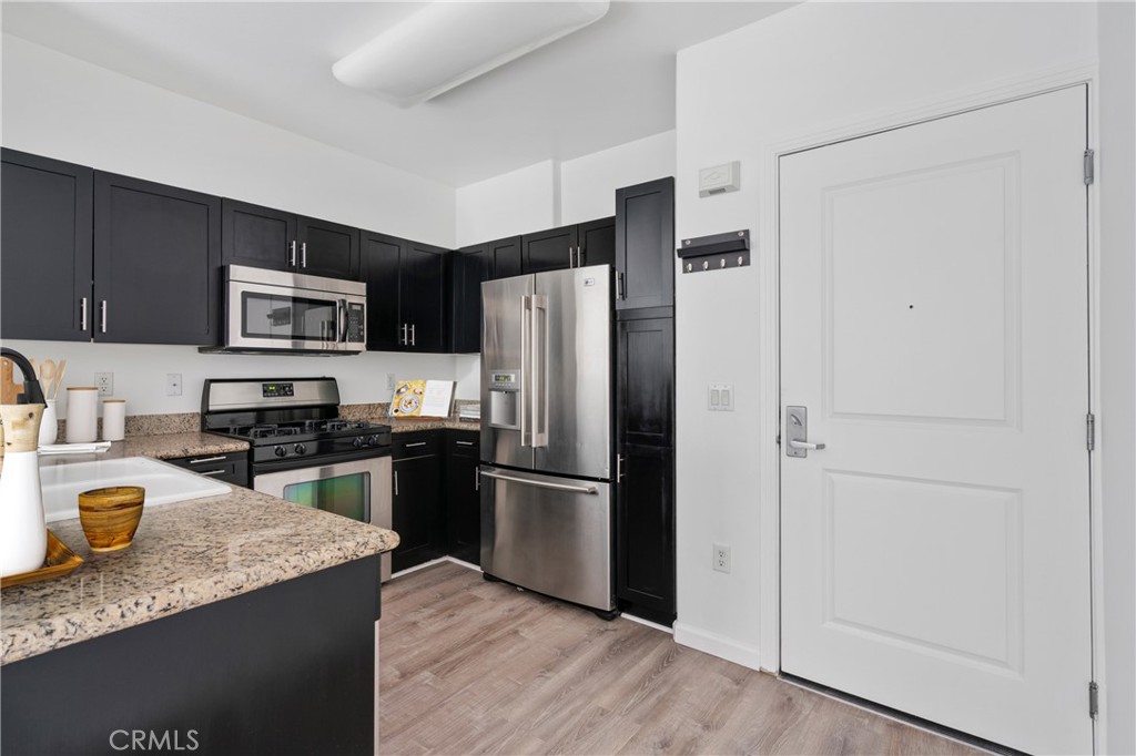 100 South Alameda Street, Unit 213 Los Angeles, CA 90012 - Photo 2 of 41 a kitchen with granite countertop stainless steel appliances and a refrigerator
