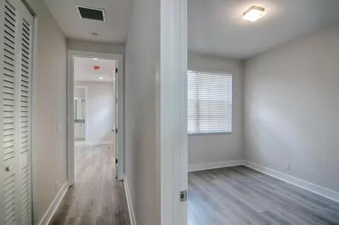 a view of an empty room with wooden floor and a window