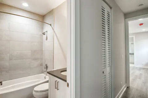 a bathroom with a granite countertop bathtub shower sink vanity and toilet