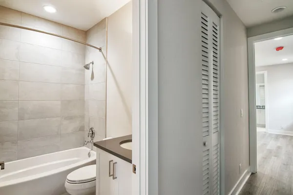a bathroom with a granite countertop bathtub shower sink vanity and toilet