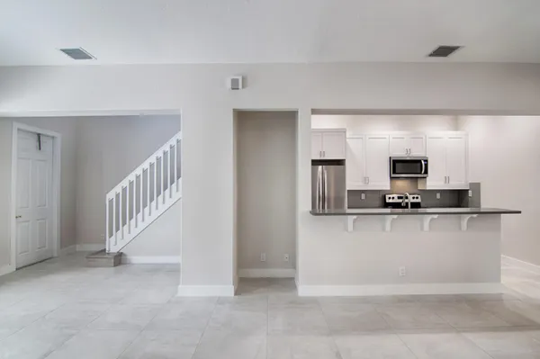 a view of a kitchen with kitchen island with stainless steel appliances wooden floor and living room view