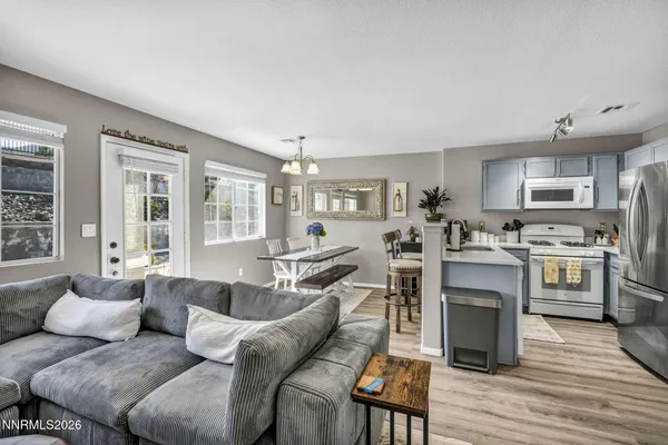a living room with stainless steel appliances kitchen island granite countertop furniture and a wooden floor