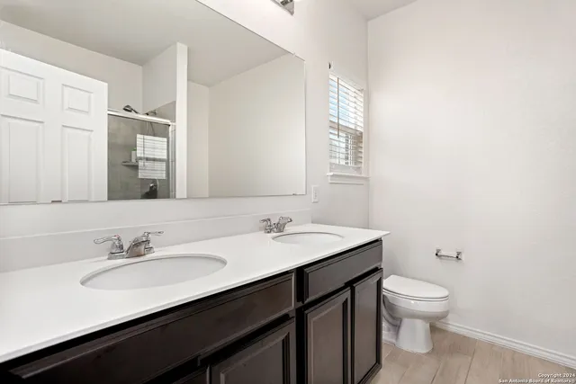 a bathroom with a granite countertop sink a toilet and a mirror