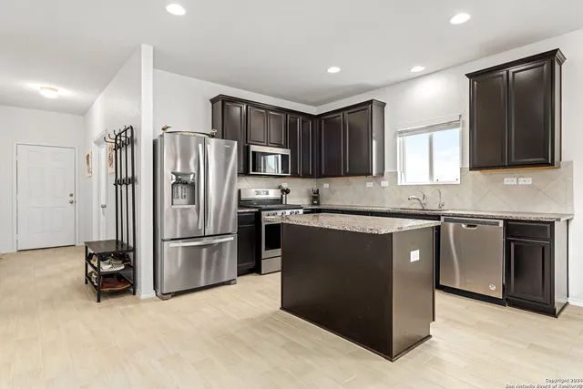 a kitchen with stainless steel appliances granite countertop a refrigerator and a stove top oven