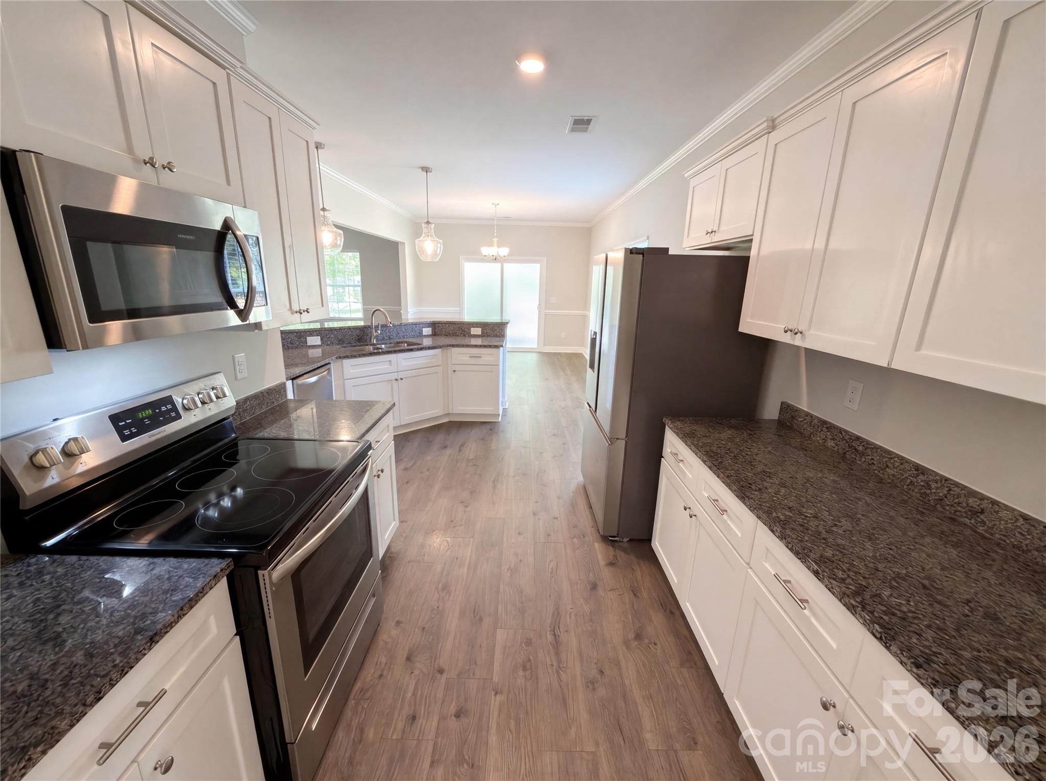 4918 Griffith Road Monroe, NC 28112 - Photo 2 of 17 a kitchen with a refrigerator a stove top oven a sink and dishwasher with wooden floor