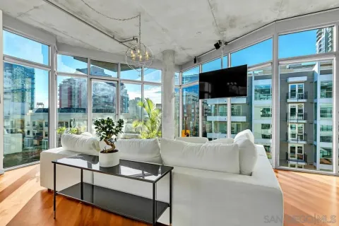 a living room with furniture a flat screen tv and floor to ceiling window