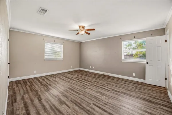 a view of an empty room with a window and wooden floor