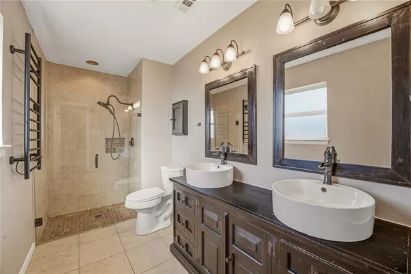 a bathroom with a double vanity sink toilet mirror and shower