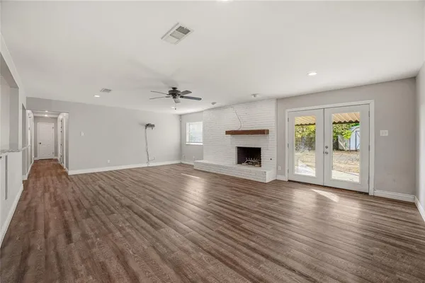 an empty room with wooden floor fireplace and windows