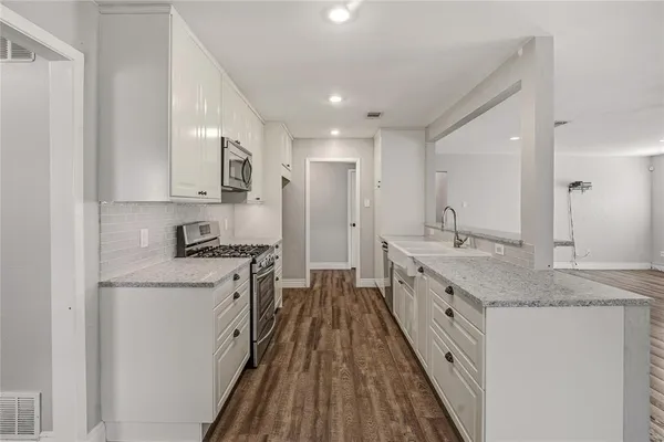a large kitchen with stainless steel appliances granite countertop a lot of counter space and wooden floor