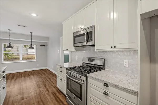 a kitchen with granite countertop wooden cabinets stainless steel appliances and a window