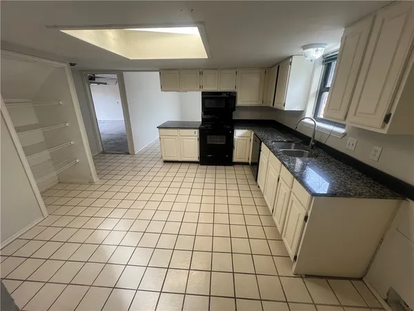 an empty room with windows and chandelier fan