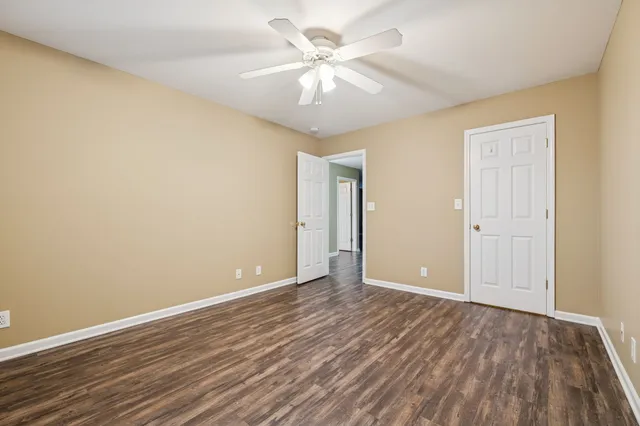 an empty room with wooden floor and a ceiling fan