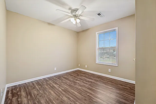 an empty room with windows and fan