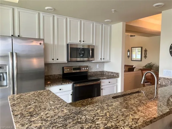 a kitchen with granite countertop a stove a sink and a refrigerator