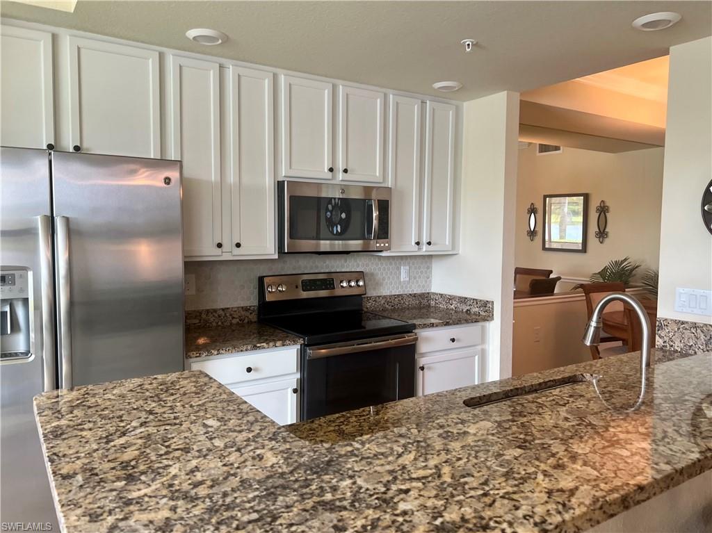 9518 Avellino Way, Unit 2313 Naples, FL 34113 - Photo 17 of 30 a kitchen with granite countertop a stove a sink and a refrigerator