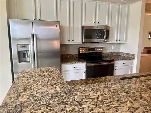 a kitchen with stainless steel appliances granite countertop a refrigerator stove and microwave