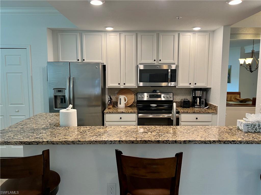 9518 Avellino Way, Unit 2313 Naples, FL 34113 - Photo 19 of 30 a kitchen with granite countertop stainless steel appliances a refrigerator a stove a sink and a microwave