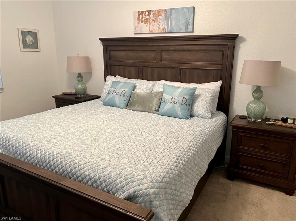 9518 Avellino Way, Unit 2313 Naples, FL 34113 - Photo 22 of 30 a bed sitting in a bedroom next to a lamp