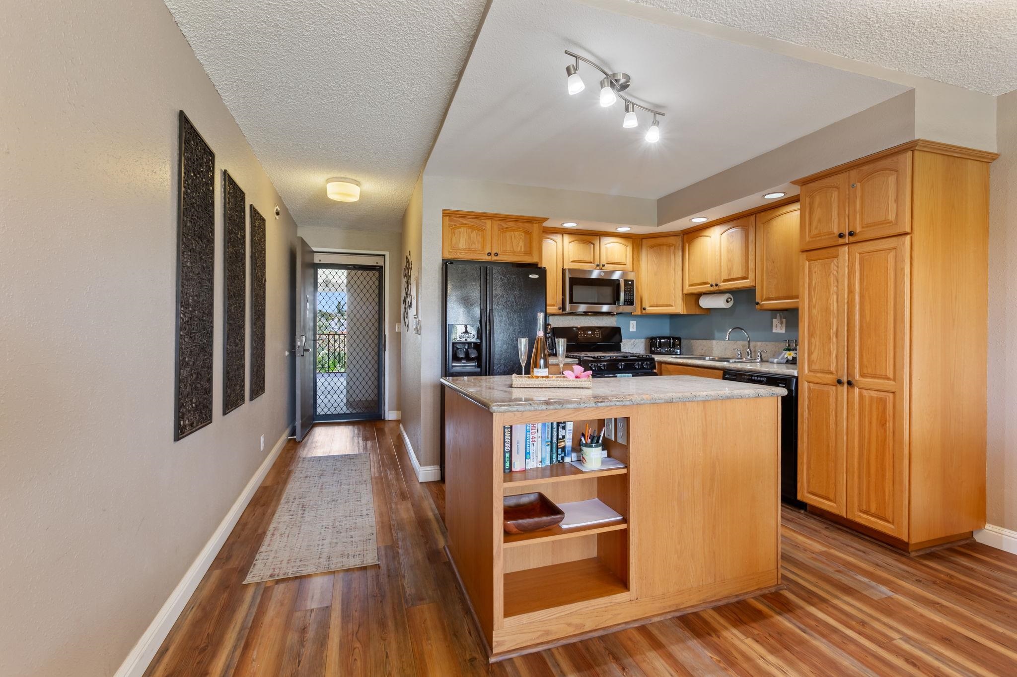 2531 South Kihei Road, Unit C414 Kihei, HI 96753 - Photo 17 of 47 a kitchen with stainless steel appliances granite countertop a refrigerator a sink dishwasher a stove and a dining table with wooden floor