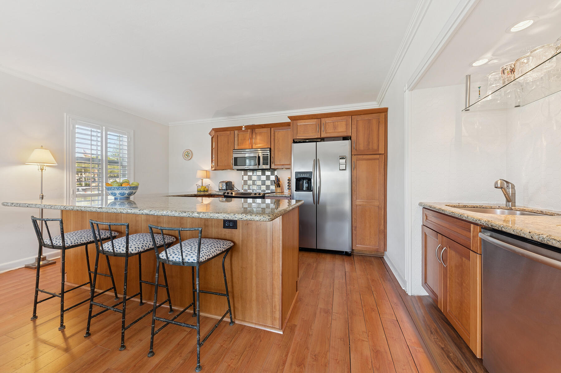 3883 Gulf Stream Road, Unit 1N Gulf Stream, FL 33483 - Photo 3 of 30 a kitchen with stainless steel appliances kitchen island granite countertop a refrigerator a stove a sink and dishwasher with wooden floor