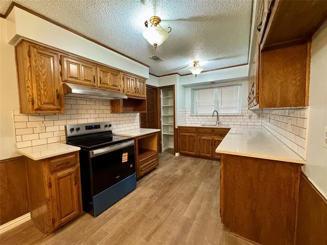 a kitchen with stainless steel appliances granite countertop a sink a stove and a wooden floors