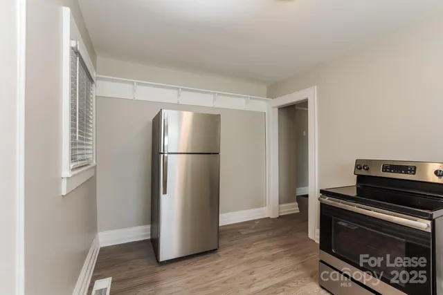 a view of a kitchen with refrigerator and wooden floor