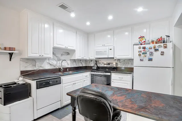 a kitchen with granite countertop white cabinets and white appliances