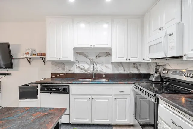 a kitchen with stainless steel appliances granite countertop a stove a sink and white cabinets